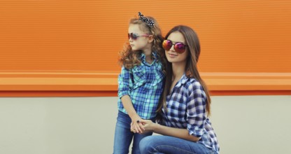Beautiful stylish mother and child daughter together, happy mom with kid girl in glasses, casual