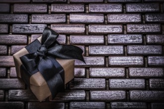 Wrapped present box with black ribbon on wicker wooden mat