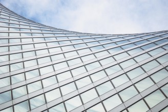 Modern architecture, glass exterior structure, wave shape building detail in blue sky