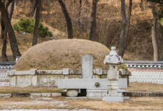 Chungju, South Korea, December 18, 2018: Burial mound surrounded by concrete wall and small statues