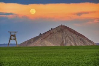A view of an overburden heap in saxony-anhalt with a winding tower at moonrise