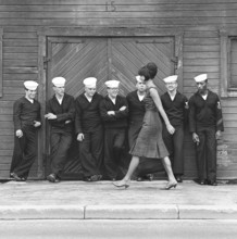 Fashion in the 1960s. A group of American sailors are standing at the docks on shore leave and
