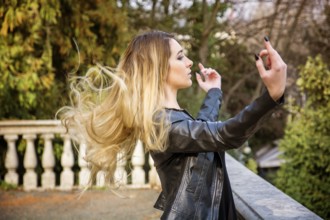 Side view of young woman standing near parapet with her hair flying in the air and outstretched
