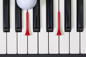 Virtuosic game - Piano keyboard and different golf balls and wooden tees