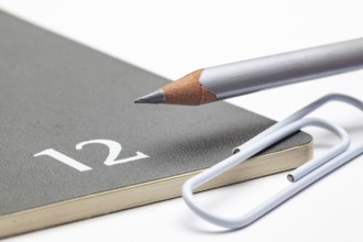 Organizer for the month of December, silver pencil and white paperclip on the white table