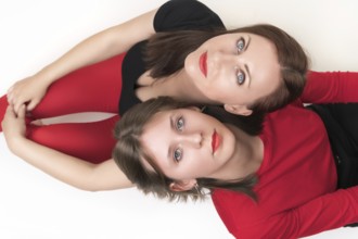 Top view of mom and daughter sitting with their backs to each other and put their heads on each