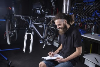 Bicycle Workshop Technician Doing Administrative Work. Bicycle mechanic writing in his checklist