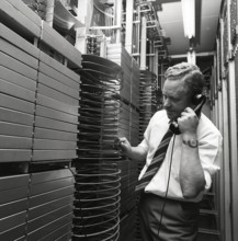 Telephony in the 1970s. A man in a room with an automatic switchboard connecting the calls through
