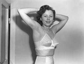 Woman of the 1940s. A young woman in a photographers studio. She holds up her arms and hands and