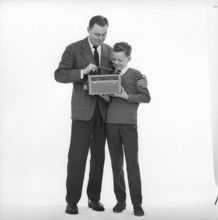In the 1960s. Father and son with a radio. It's a typical 1960s radio with a cover of perforated