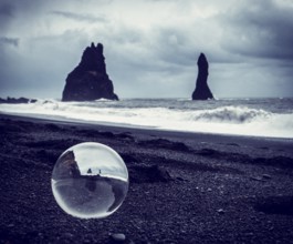 Cold sea water rolling on wet sand near rough stony cliffs on stormy day on Reynisfjara Black Beach