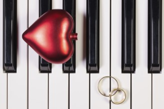 Detail of piano keyboard, red heart and wedding rings