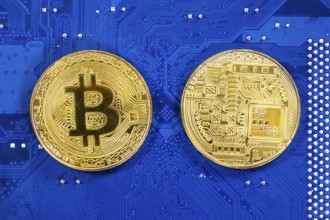 Virtual cryptocurrency money Bitcoin golden coins on a computer printed circuit board PCB. The