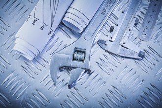 Blueprints vernier scale caliper monkey spanner on channeled metal background construction concept