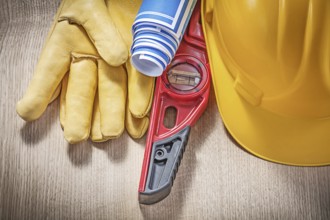 Building helmet safety gloves construction level blue blueprint rolls on wooden board