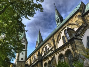 An imposing church with several towers against a blue sky, surrounded by trees, Werl, North