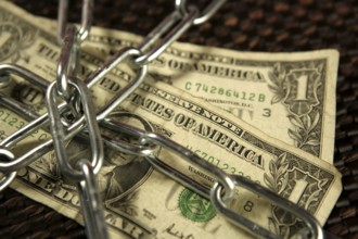 One Dollar notes in chains studio shot over brown background