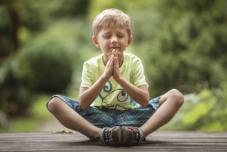5-6 years old boy meditates in the park
