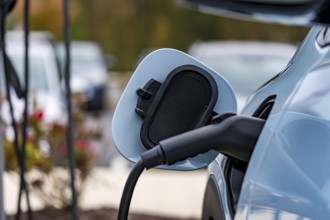 An electric vehicle recharges at a station while its owner is at work, allowing for a fully charged