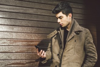 Portrait of young handsome Turkish male model of Mediterranean race brunet in leather coat using