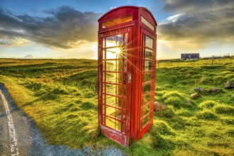 Urban red telephone box in the middle of a green countryside. Concept for synergy between modern