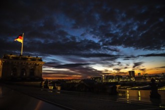 The Berlin Reichstag with evening sky with the flag of Germany and clouds in the background. The
