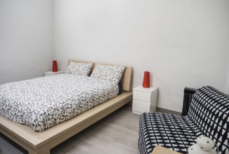 Small cozy bedroom interior furnished with comfortable soft bed and chair in contemporary apartment