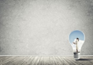 Businesswoman inside of light bulb in empty concrete room