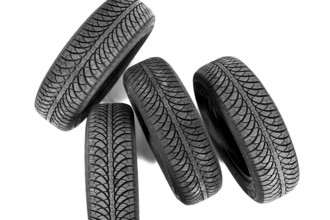 Isolated on white, four new black rubber automobile tires with protector standing