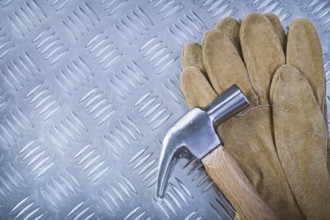 Claw hammer leather protective gloves on fluted metal background construction concept