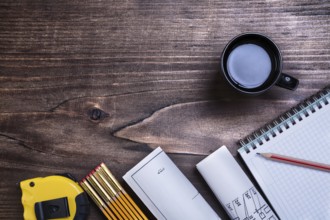 Checked copybook pencil blueprints tape line wooden meter and cup of coffee on wood board