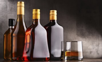 Composition with glass and bottles of assorted alcoholic beverages
