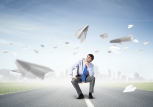 Young businessman sits on an office chair, thoughtful and looking up