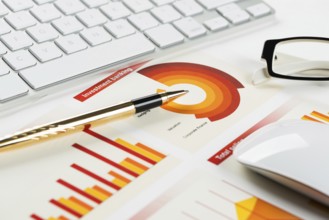 Business workplace with keyboard glasses and financial documents on table