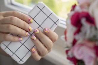 Stylish summer colorful nails female manicured hands holding mobile phone. Closeup of manicured