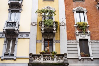 Facade of the building with stucco, balconies and flowerpots. Milan, Italy.