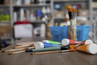 A colorful assortment of art supplies and brushes arranged on a wooden table in an artistic setting