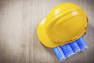Wooden board with blue blueprints building helmet construction concept