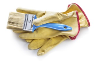 Blue paintbrush on yellow leather working gloves isolated