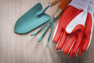 Rubber red safety gloves hand shovel and gardening rake on wooden board agriculture concept