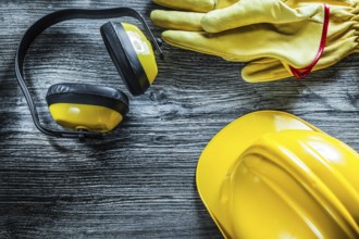 Earmuffs protective gloves hard hat on wooden board