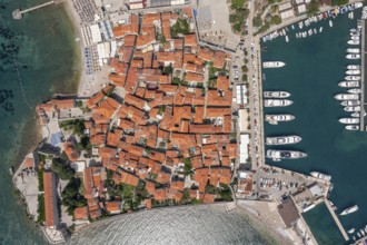 Aerial top view of walled old town of Budva city. Pier with moored yachts and boats. Adriatic sea,