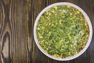 Celtic cake with spinach, tomatoes, oatmeal and eggs in baking dish from a foil against the