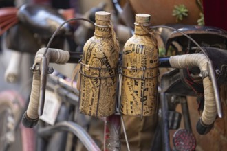 Two retro bottles attached to an old bicycle handlebar, at the legendary L'Eroica cycling race,