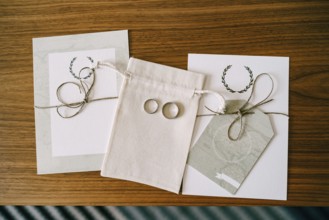 Gold wedding rings on a fabric bag between the leaves with the vows of the bride and groom.