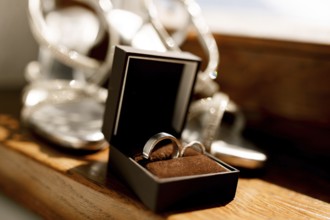 Wedding rings in an open brown box on the floor with women's wedding sandals on a blurred