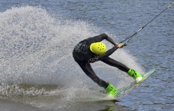 Russia, Volgodonsk - June 18, 2015: Water snowboard. The athlete with snowboard hold on to the rope