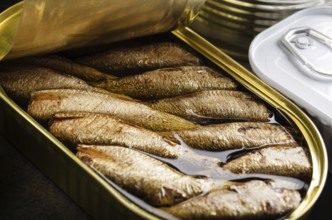 Canned smoked fish sprats in just opened tin can. Non-perishable food