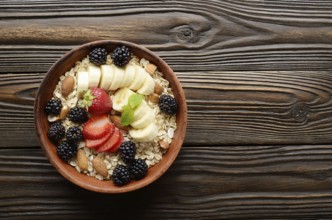 Flat lay top view at Fruit healthy muesli with banana strawberry almonds and blackberry in clay