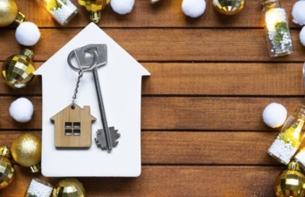 Key to house with a keychain tiny home on wooden background with Christmas decor layout. Gift for